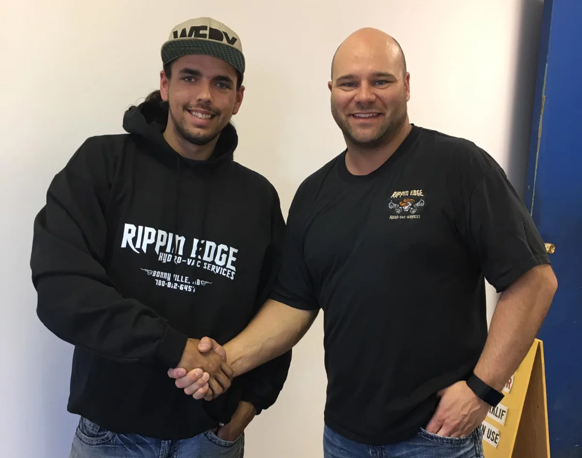 Two men shaking hands, wearing Rippin Edge logo apparel